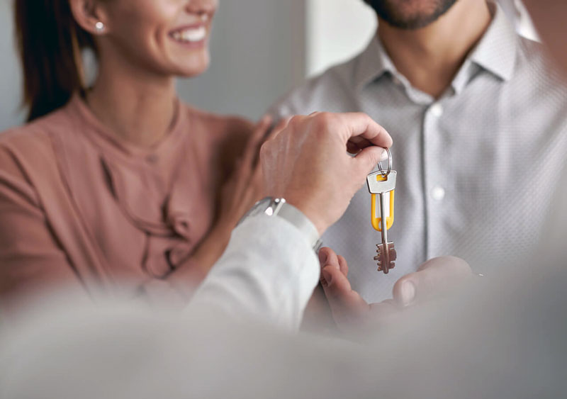 Wohnungssuche in Hamburg mit dem Landeplatz-Team: Das Bild zeigt eine schlüsselübergabe an ein lachendes Paar.